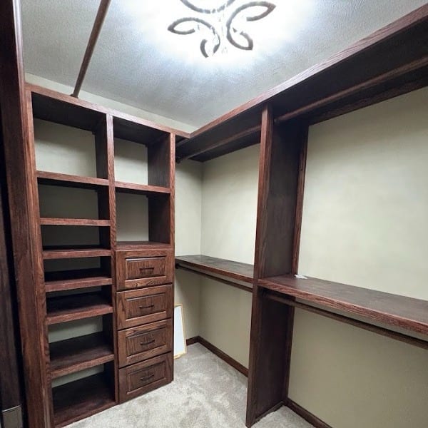 Custom walk-in closet system with stained shelving and a drawer bank, built by JAKS