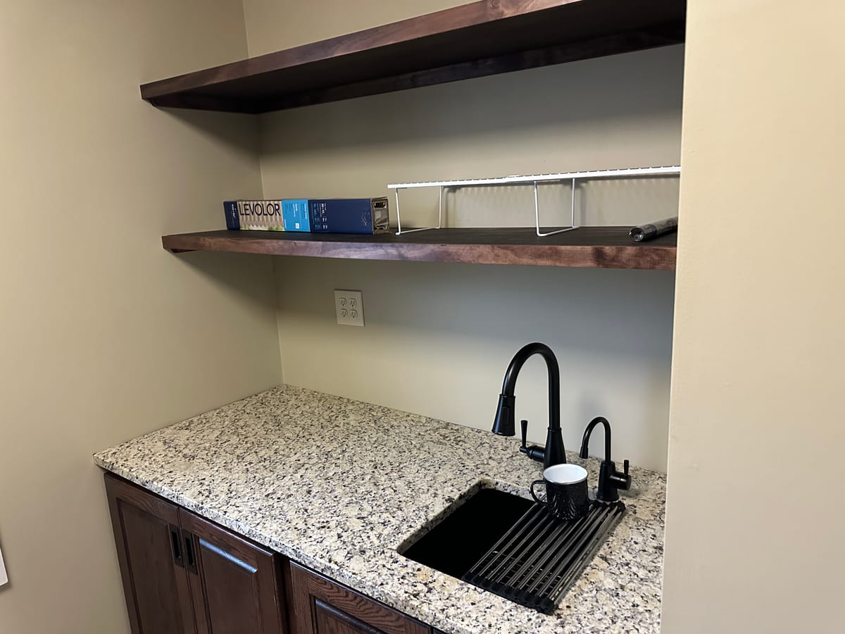 Custom basement wet bar with granite counter and floating shelves built by JAKS Construction in Maize, Kansas